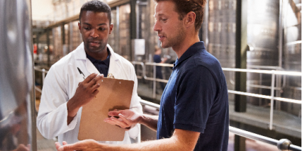 man in lab coat talking to worker