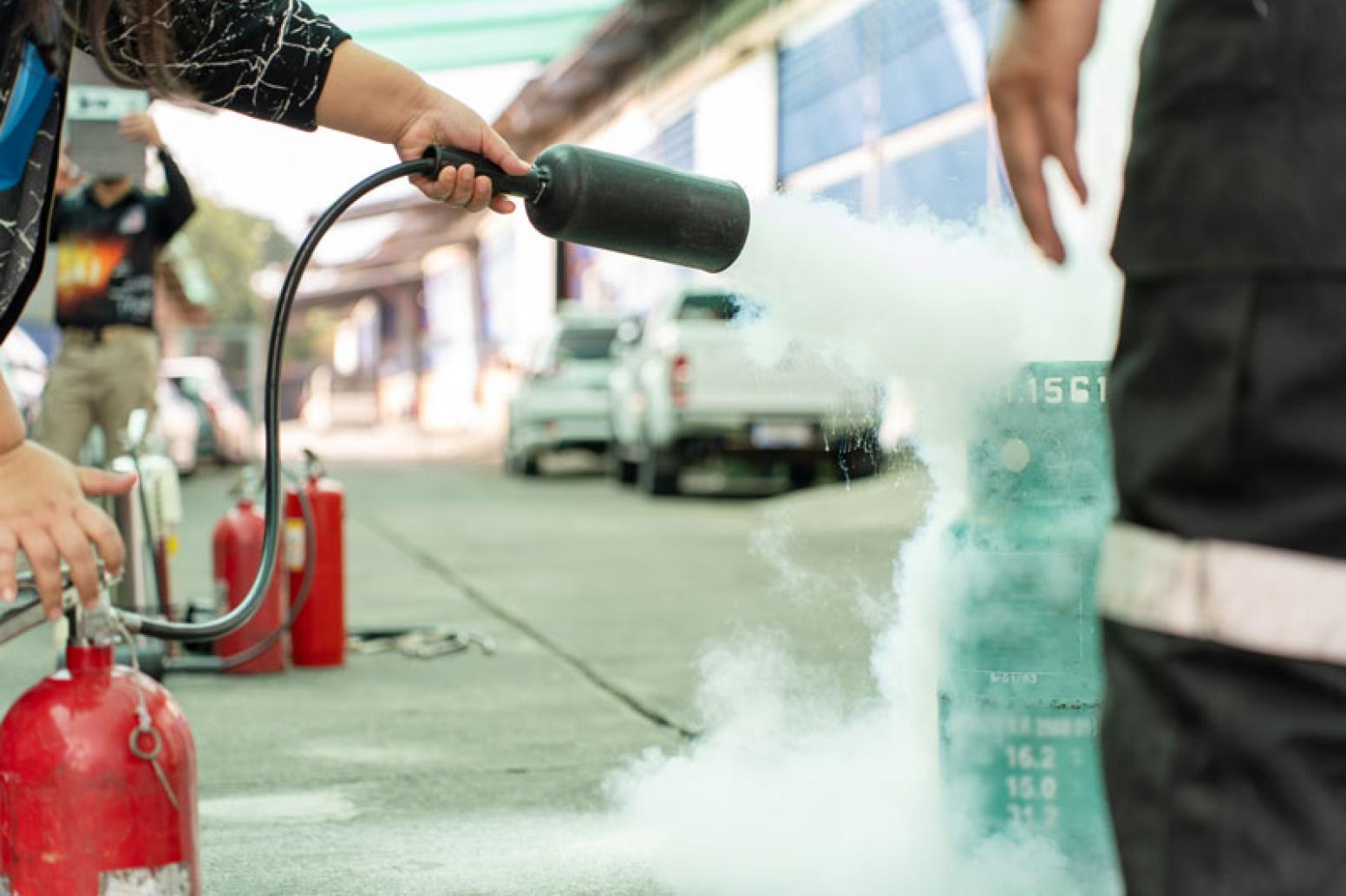 A bruin using a fire extinguisher at a fire safety event