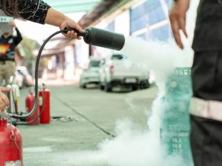 A bruin using a fire extinguisher at a fire safety event